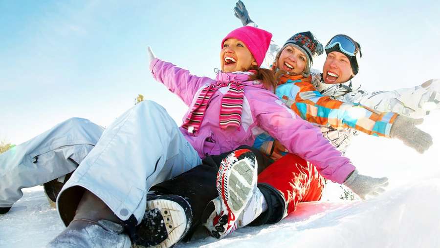 ludzie zjeżdżają po śniegu na sankach